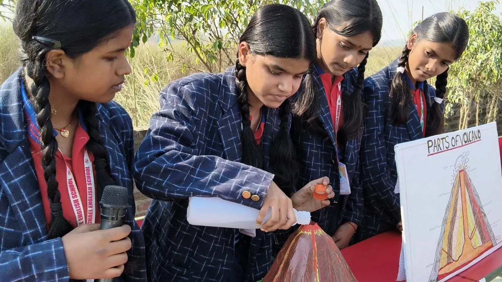 A student explaining a hand-made model of the parts of a volcano to visitors at the school science exhibition