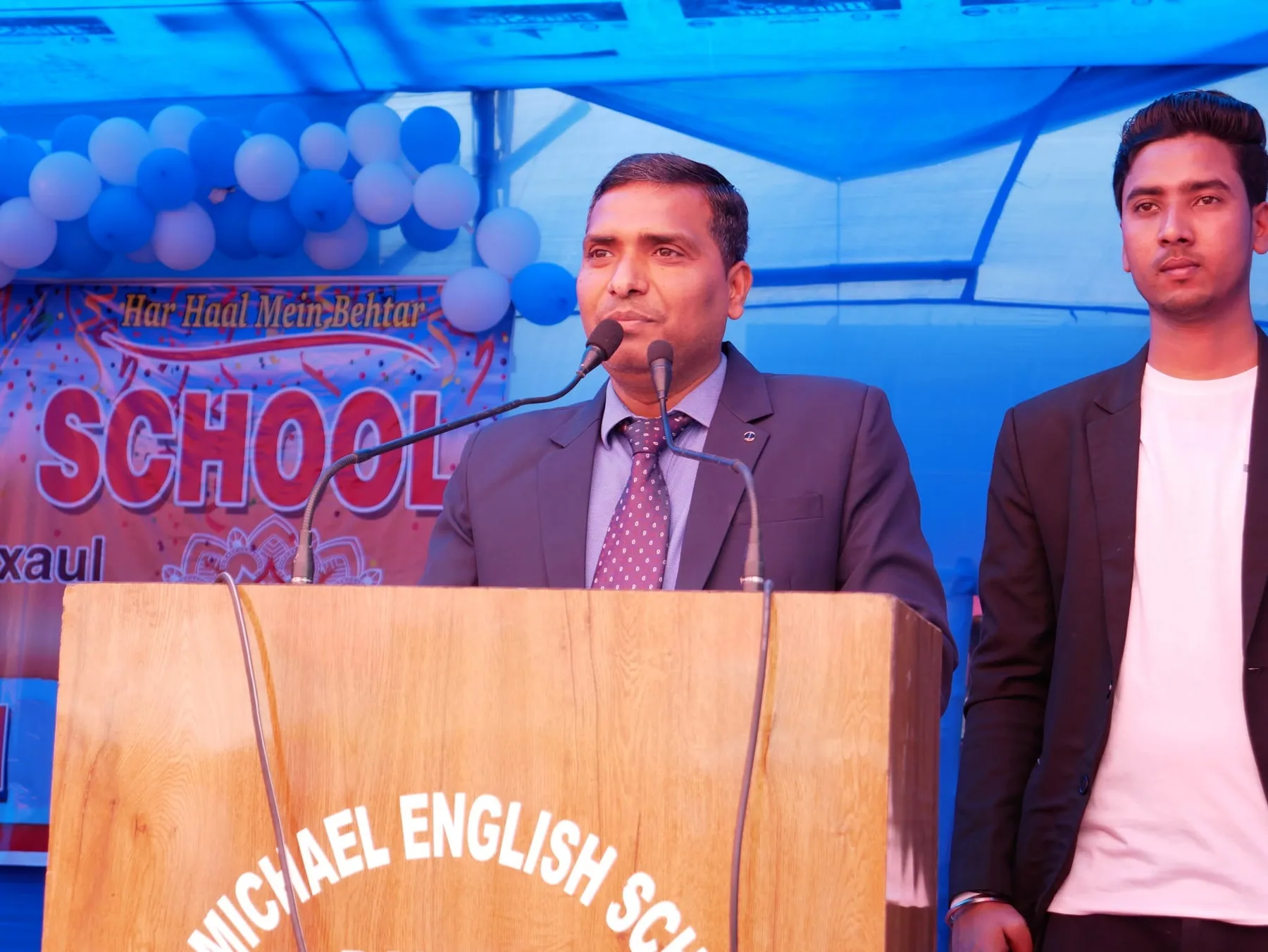 A member of staff addressing the audience from a lectern at the annual day celebration