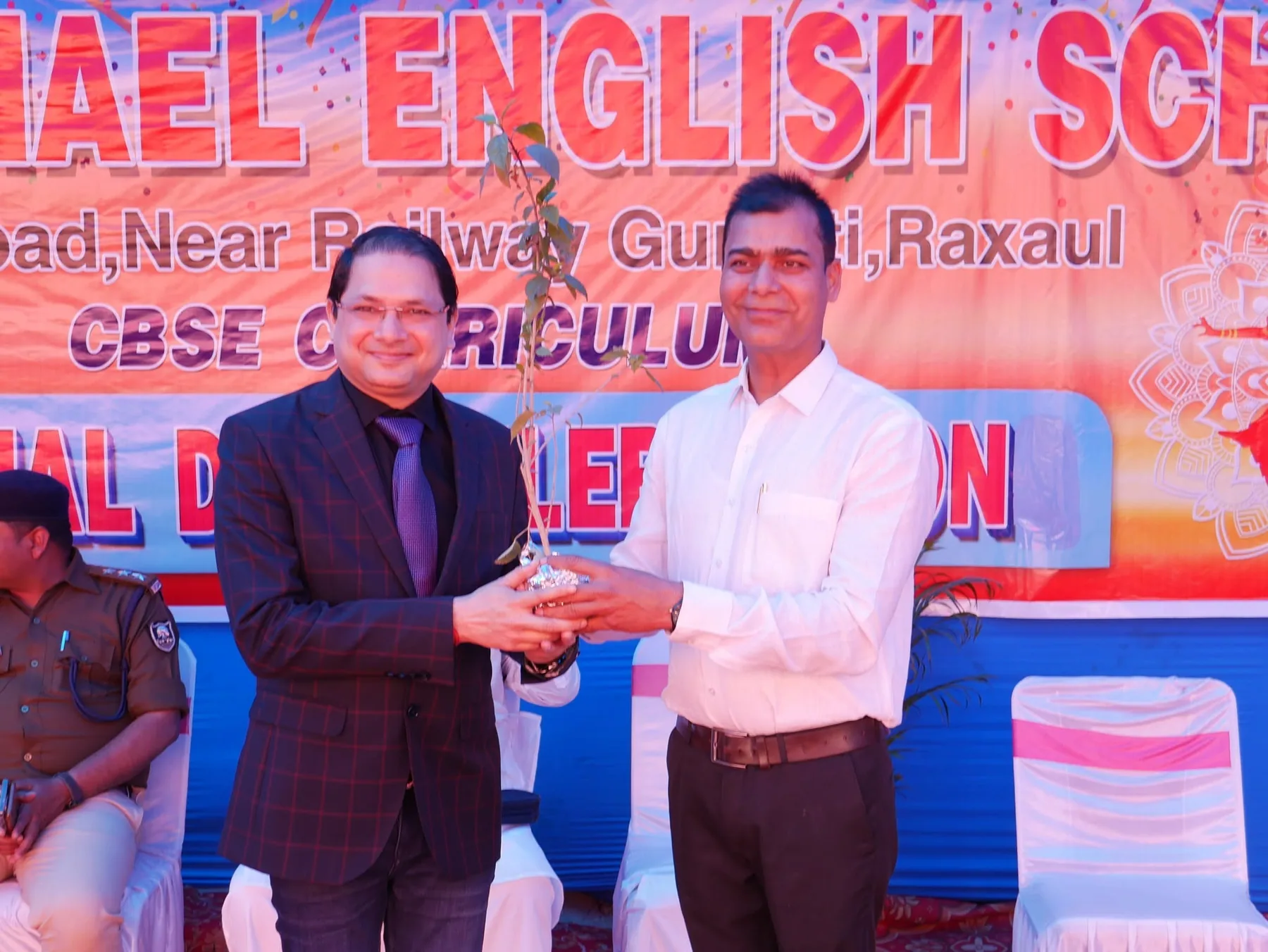 A trophy being presented on stage in front of the school annual day banner