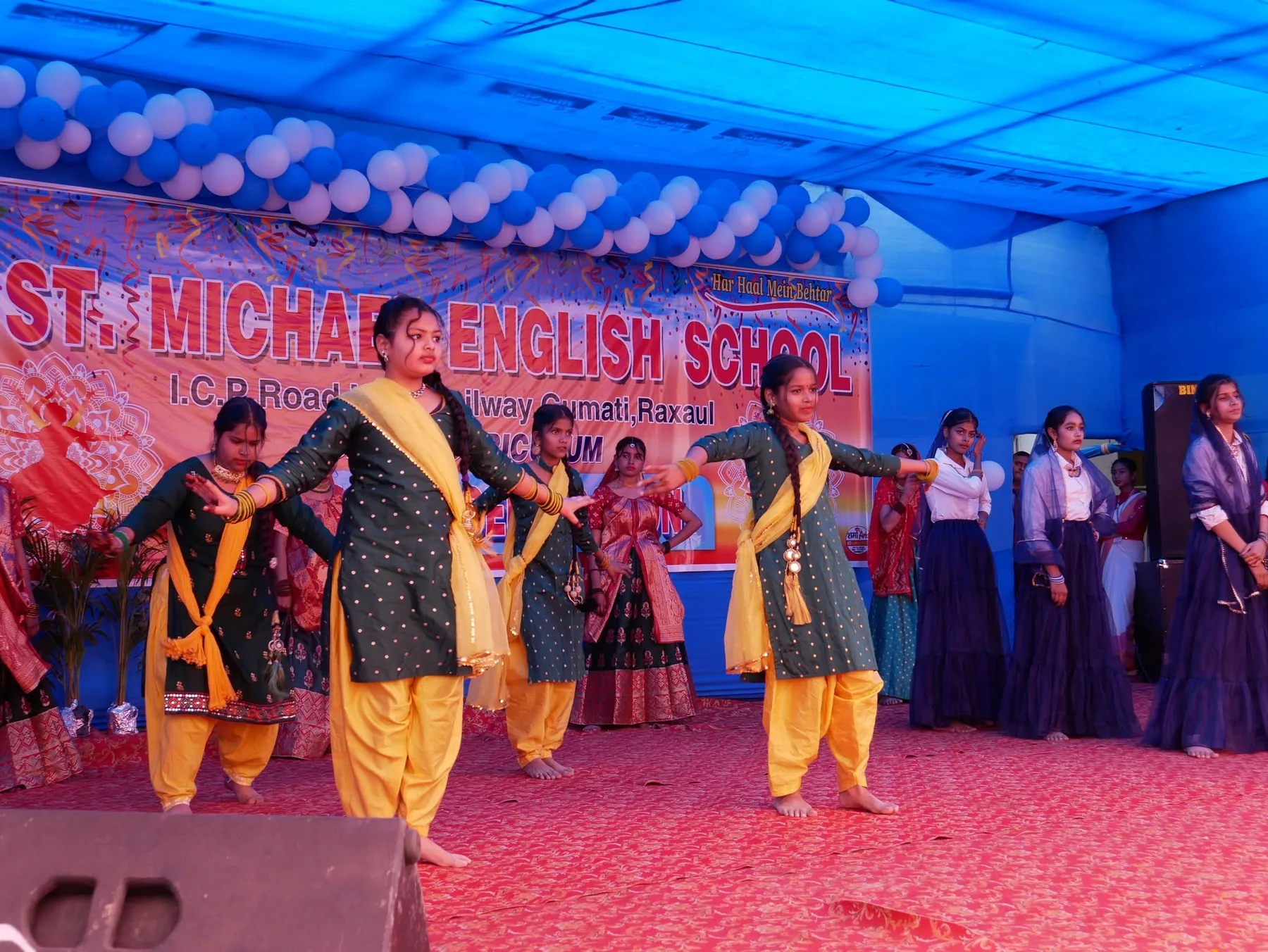 Students performing on stage beneath a banner reading St. Michael English School