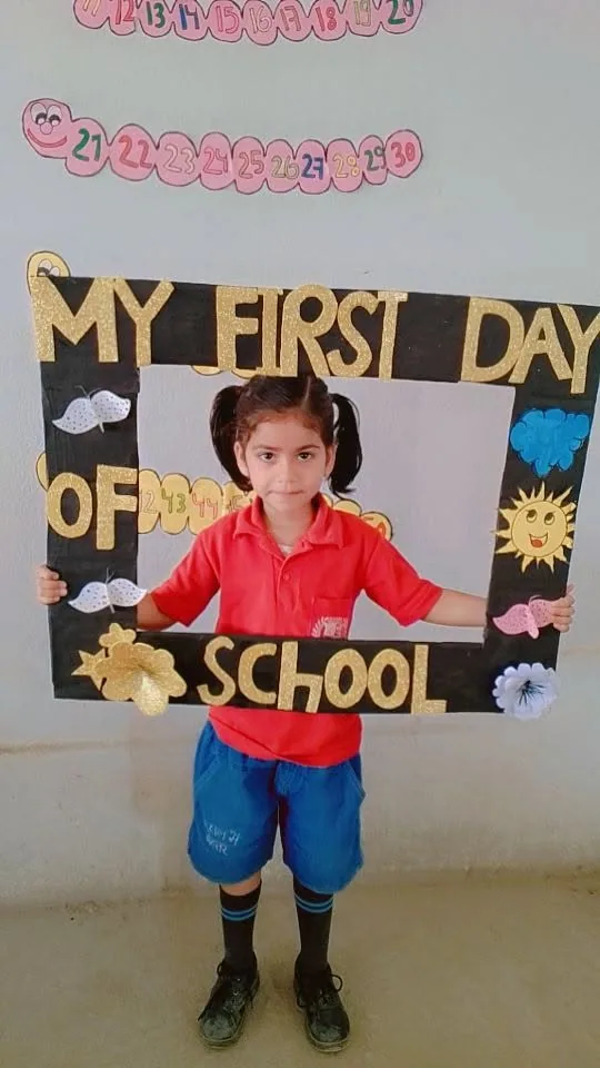 A new pupil standing inside a decorated "My First Day of School" photo frame