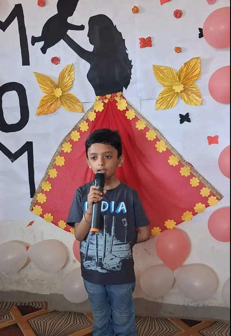 A young student speaking into a microphone in front of a decorated backdrop
